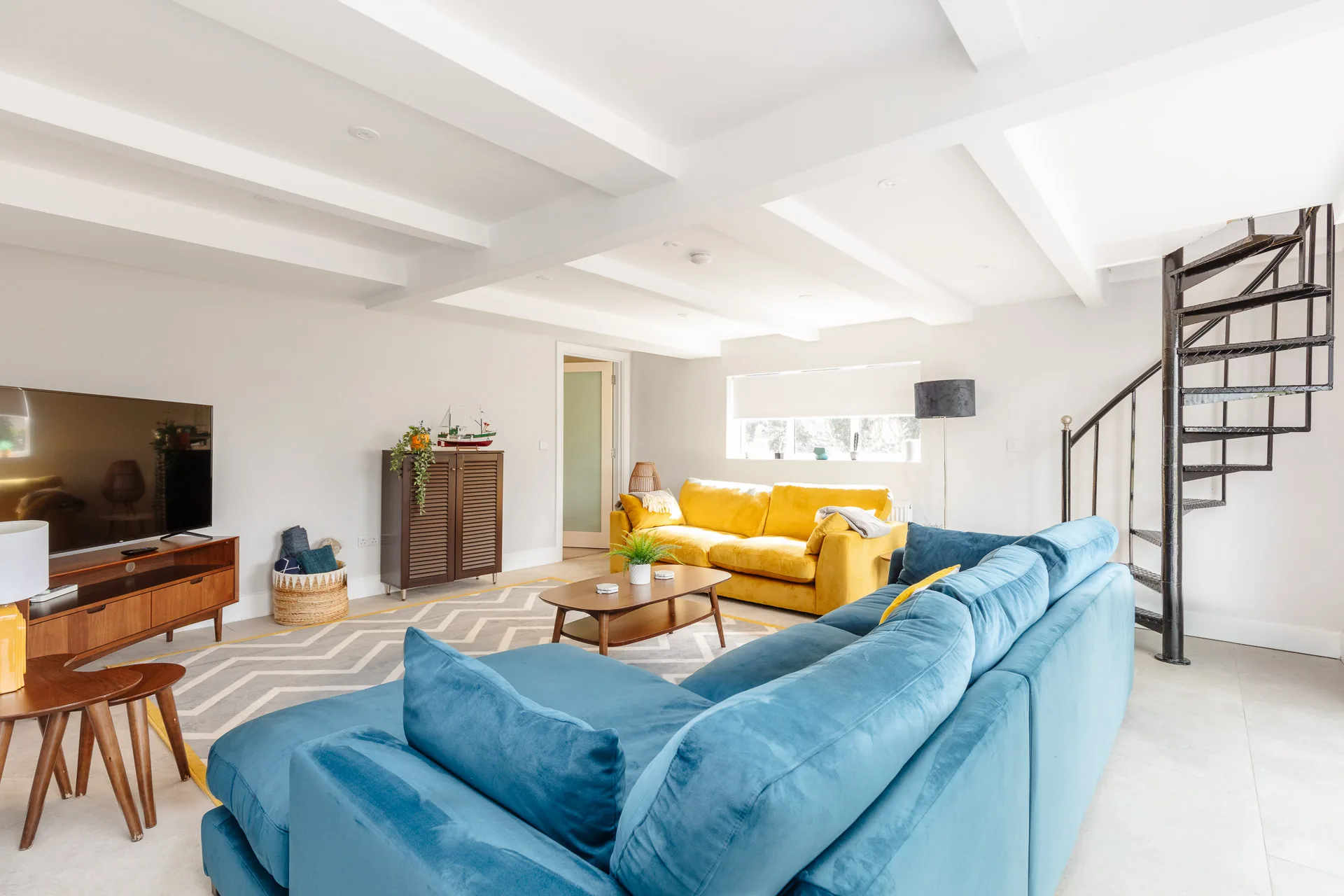 Living room with blue sectional and yellow sofa